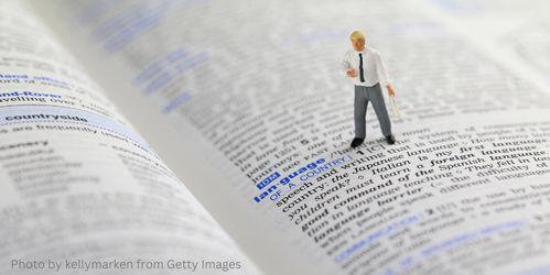 An open page in a dictionary with a little figure of a man standing on it