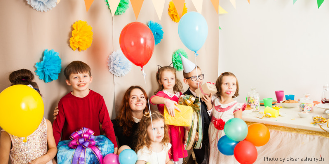 Children having fun at a Christmas party with decorations, paper hats, balloons and food on the table