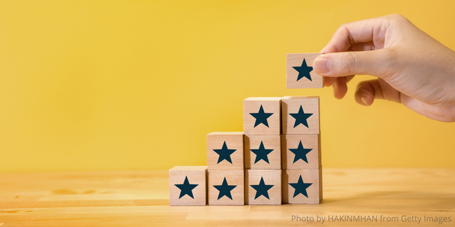 A hand building with little wooden blocks with stars on them.