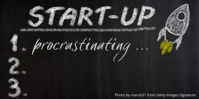 A blackboard with a rocket drawn with chalk and the words "Start up" and "procrastinating"