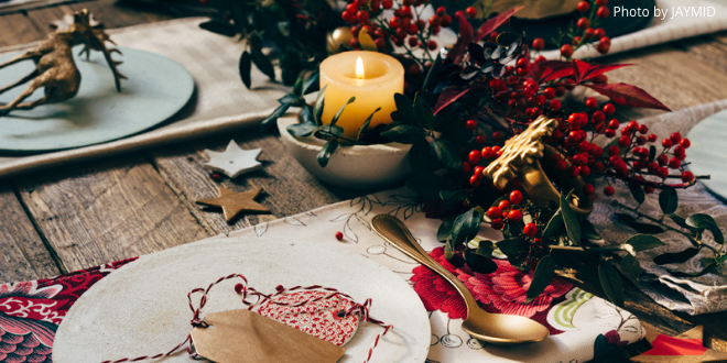 A Christmas table with place tags, candle, garland and napkin