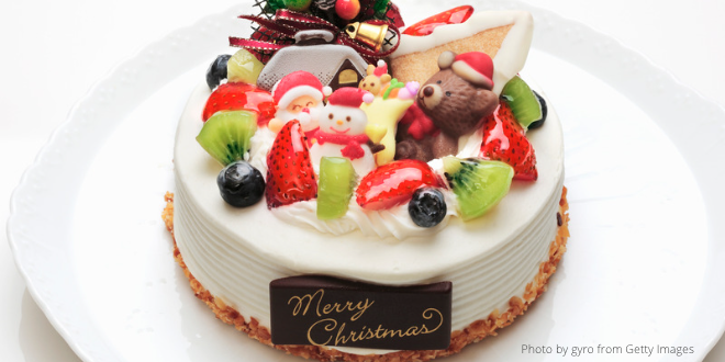 A small round Christmas cake decorated with white icing and all kind of goodies on top