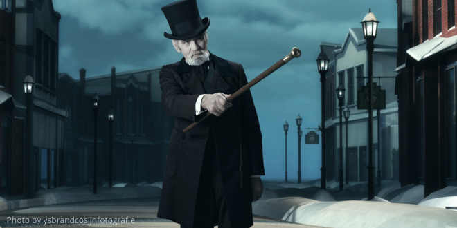 A man in a black coat and top hat with a cane in his hand