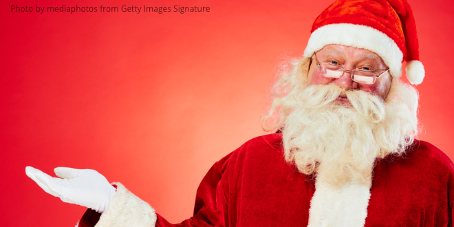 Santa Claus standing with one hand open in front of a red background