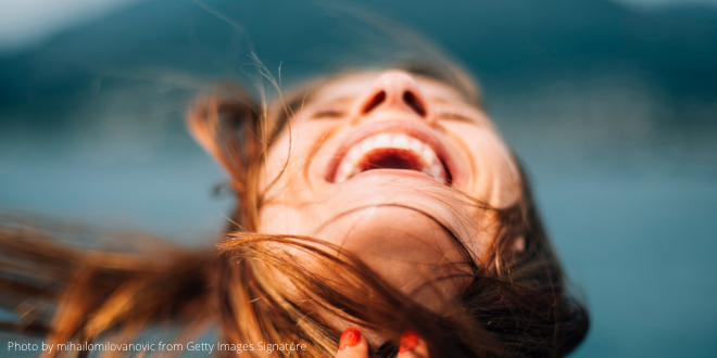 A young woman holding her head back and laughing