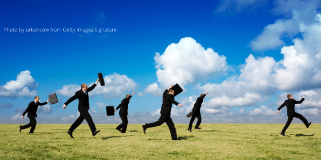 Five businessmen in black suits, each holding a briefcase, running after a man in a black suit