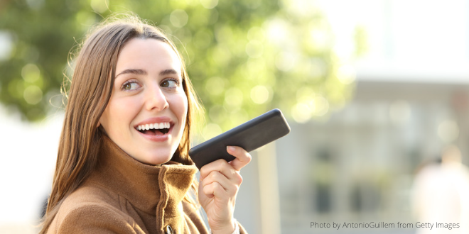 A young lady dictating a message on her mobile phone