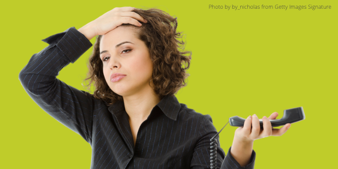 A young lady holding the receiver of a telephone in her left hand