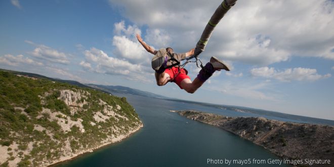 A man bungee jumping over a stretch of water