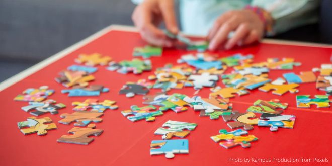 A person sitting at a table doing a jigsaw puzzle