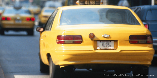 A yellow cab with a few yellow cabs in the background