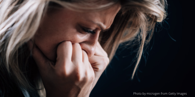 A woman pressing her mouth into her fists as if she's frightened