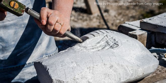 A man working with a chisel and a hammer on a piece of stone