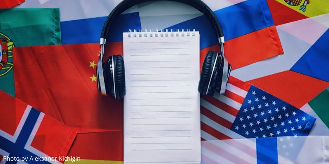 A note pad and headphones in front of a range of different flags