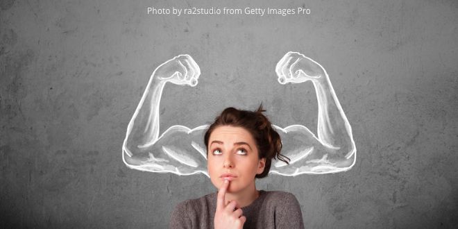 A woman standing in front of a sketch of two arms flexing their muscles