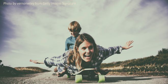 A mother and son playing with a skateboard