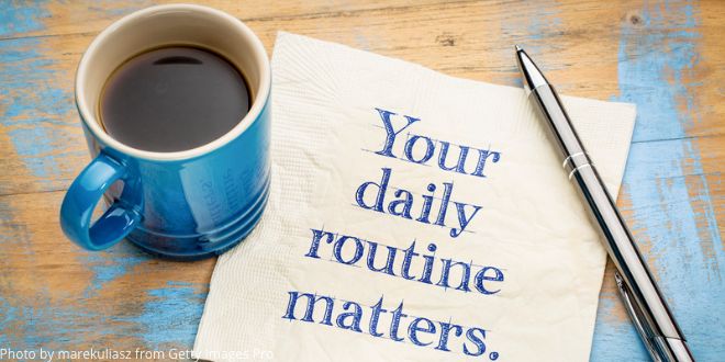 A napkin with the words "Your daily routine matters" on a table next to a mug of coffee