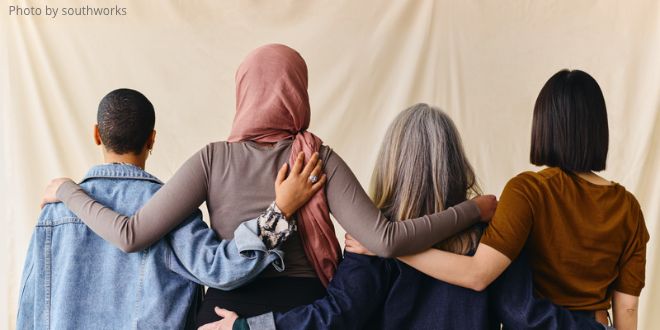 The backs of four people with arms around each other