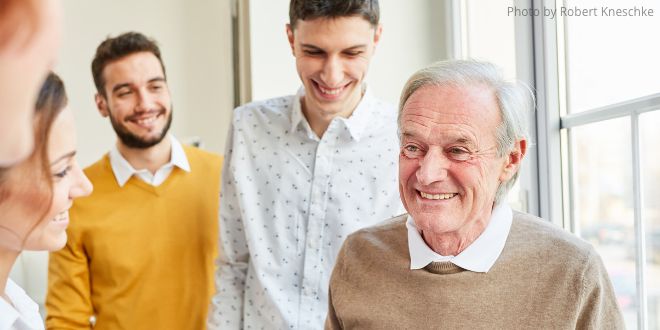 Young people speaking to an elderly man