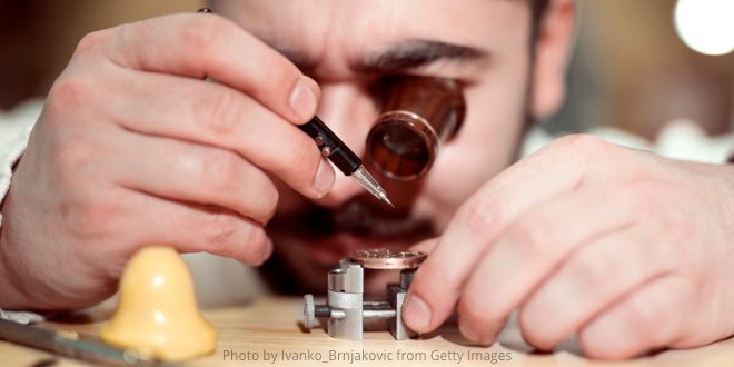 A watchmaker looking through his eyeglass working on a watch