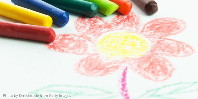 Coloured crayons on a white sheet of paper with a drawing of a flower