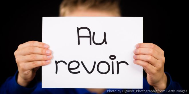 Two hands holding up a white sheet of paper with the words "Au revoir"