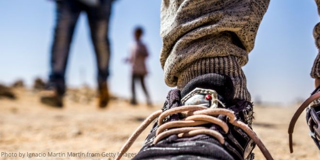 A close up of a right foot wearing a boot in the desert