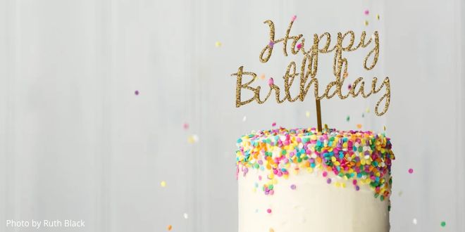 A beautiful birthday cake decorated with a Happy Birthday banner and colourful sprinkles