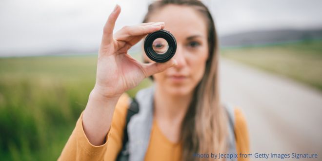 A woman holding a camera lens up to her eye