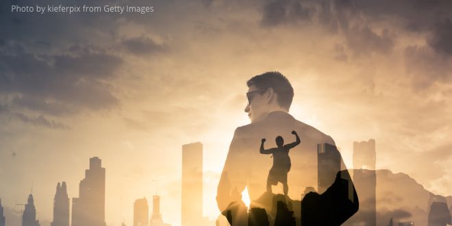 A multiple exposure picture of buildings in the background and a man in the foreground and a superman within the man!