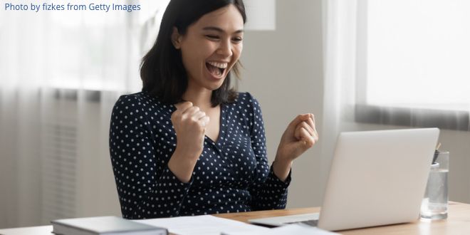 A young woman looking very excited in front of her laptop