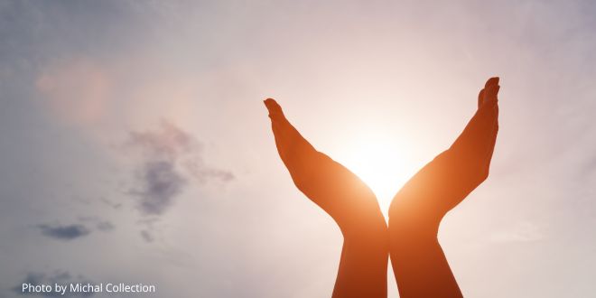 Hands held upwards towards the sky as if holding the sun