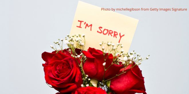 A bouquet of red roses with a note carrying the words "I'm sorry"