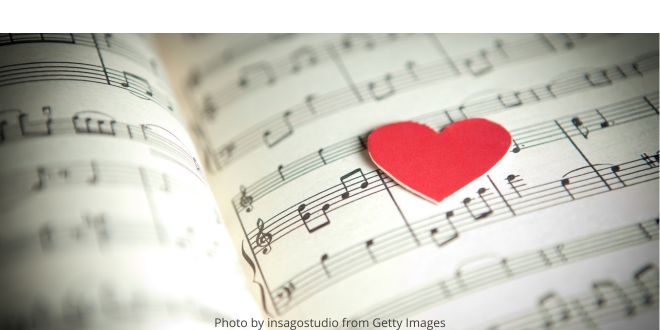 A small red heart made of cardboard on sheets of music