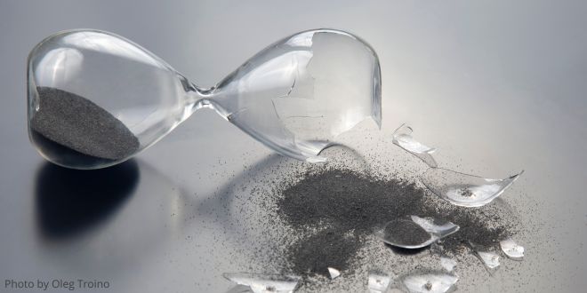 A broken hourglass with sand on the table