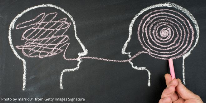 A chalk drawing on a blackboard of two faces joined by white lines