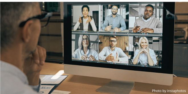 A person sitting in front of a computer screen talking to a group of people in an online meeting