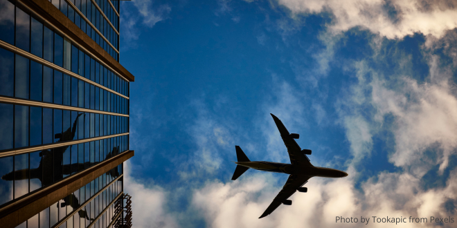 The underside of an aeroplane against a blue sky and clouds