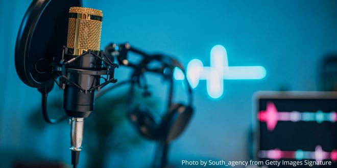 A close-up of a microphone and cables against a turquoise background