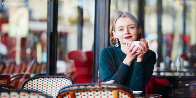 A young woman holding a cup in a Parisian café