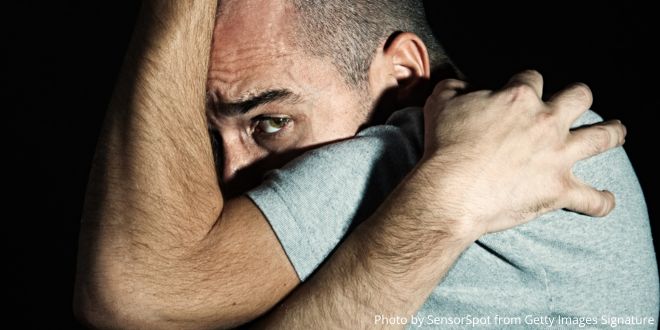 A man holding his arms and hands around his head as if hiding himself