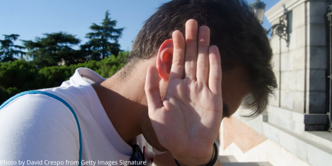 A young man with his hand hiding his face