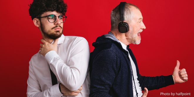 A young man turning round to look at an older man with headphones on and singing