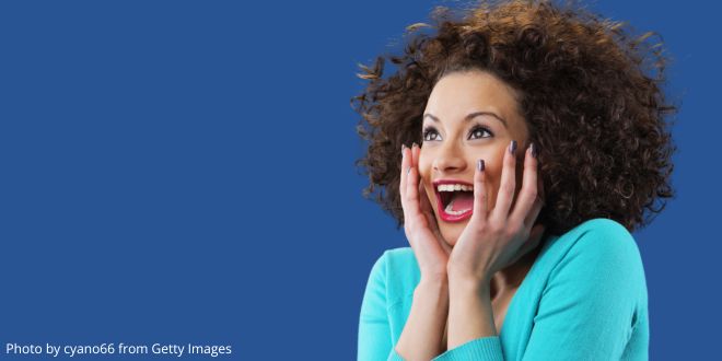 A young woman wearing a turquoise jumper looking surprised