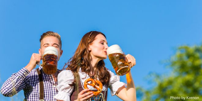 A German couple wearing traditional costumes and drinking beer and holding a pretzel