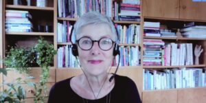 Christine in her office with a bookcase and plants in the background