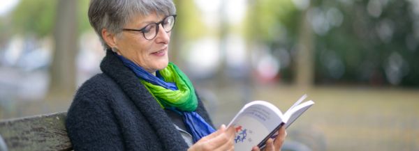 Christine Burgmer liest Christine Burgmer sitzt auf einer Bank in Köln und liest ein englisches Fachbuch