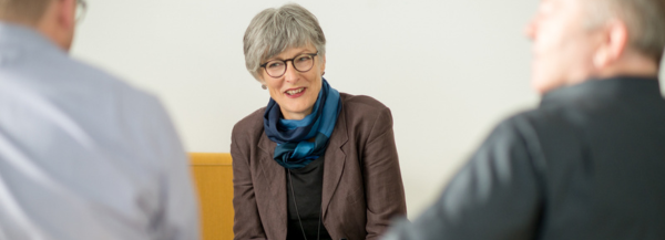 Christine Burgmer sitting in a company meeting room working with two business clilents.
